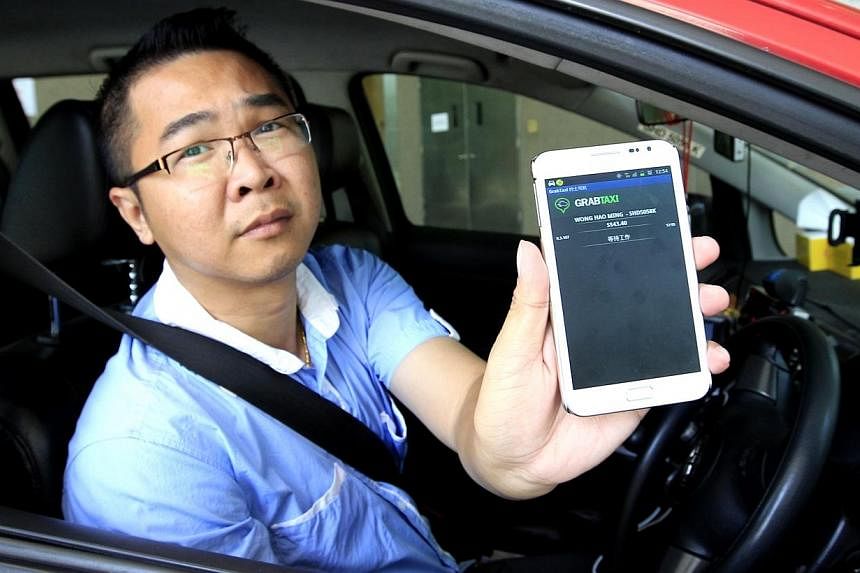 Taxi driver Wong Hao Min with his mobile app, GrabTaxi, which helps him find passengers and boost his earnings.&nbsp;-- PHOTO: ST FILE