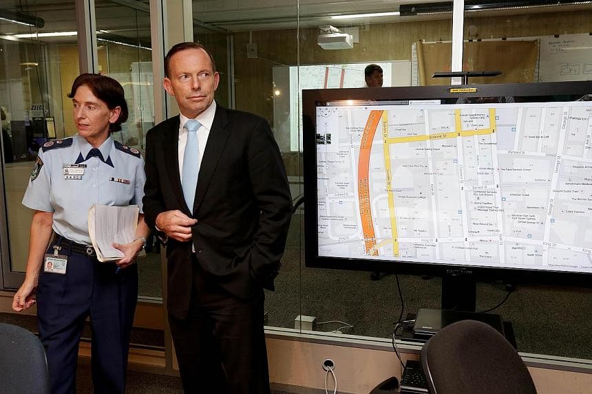 Australian Prime Minister Tony Abbott (centre) meets deputy commissioner Catherine Burn (left) as he visits the Police Operations Centre in the wake of the siege on a cafe in Sydney. -- PHOTO: AFP