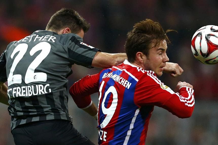 Bayern Munich's Mario Goetze (right) fights for the ball with Freiburg's Sascha Riether during their German first division Bundesliga soccer match in Munich Dec 16, 2014. Undefeated Bayern Munich outclassed Freiburg 2-0 on Tuesday to extend their lea