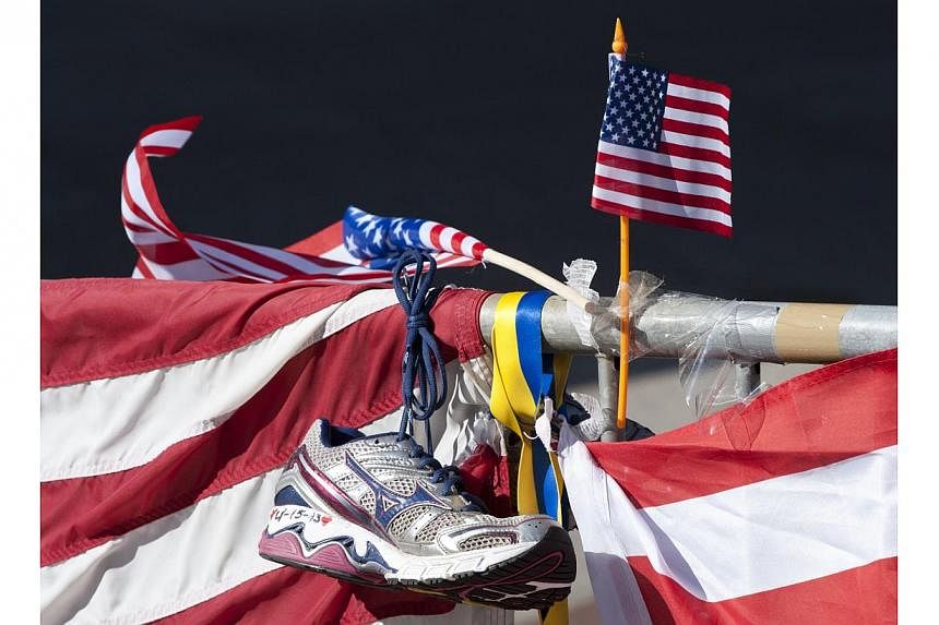A running shoe and US flag as part of a memorial on the Boston Marathon route in Boston on April 18, 2013. -- PHOTO: AFP