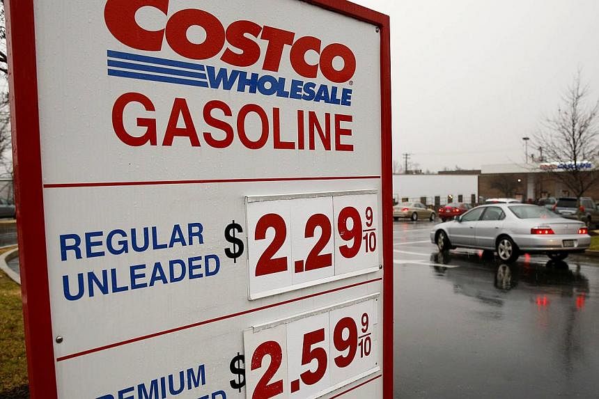 Cars lining up for regular petrol at the Costco in Beltsville, Maryland, on Dec 16, 2014. US stock index futures fell on Tuesday as a slide in the Russian rouble and crude oil prices sent traders fleeing risky assets. -- PHOTO: REUTERS