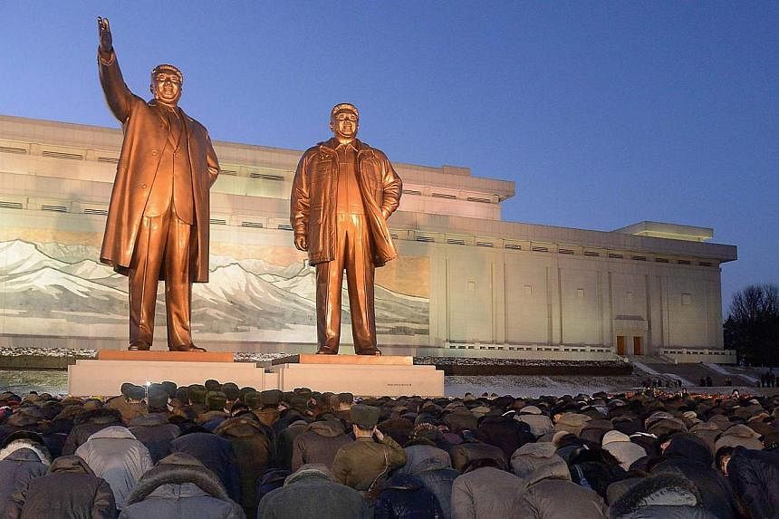 North Koreans bow to bronze statues of late North Korean leaders Kim Il Sung (left) and Kim Jong Il at Mansudae in Pyongyang. -- PHOTO: REUTERS/KYODO