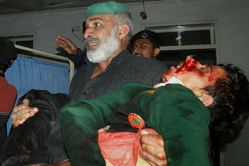 A Pakistani man carries an injured student at a hospital following an attack by Taleban gunmen on a school in Peshawar on Tuesday. Taliban insurgents killed at least 130 people, most of them children, after storming an army-run school. -- PHOTO: AFP&