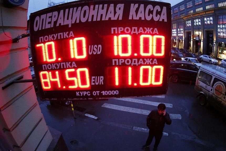 A man standing under a board showing currency exchange rates in Moscow on Dec 16, 2014. The Russian rouble crashed back to earth after an emergency hike in interest rates provided only fleeting support. -- PHOTO: REUTERS
