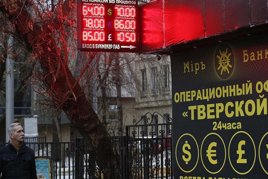 A man walks past a building and a board showing currency exchange rates in Moscow, Dec 16, 2014.&nbsp;At the exchange points that are a fixture across the Russian capital, those in need of dollars to protect their savings from the rouble collapse wer