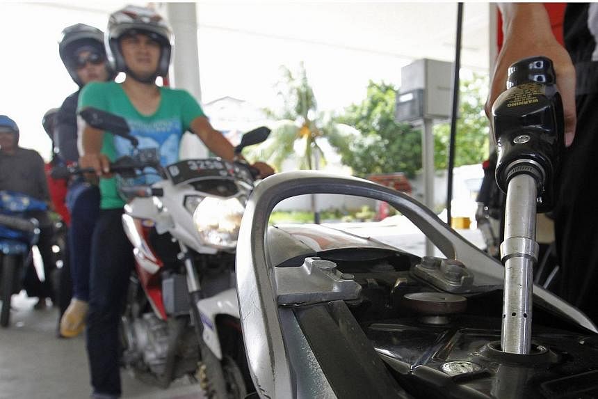 An employee of state-owned Pertamina refuelling a motorcycle at its petrol station in Jakarta on Dec 17, 2014. -- PHOTO: REUTERS