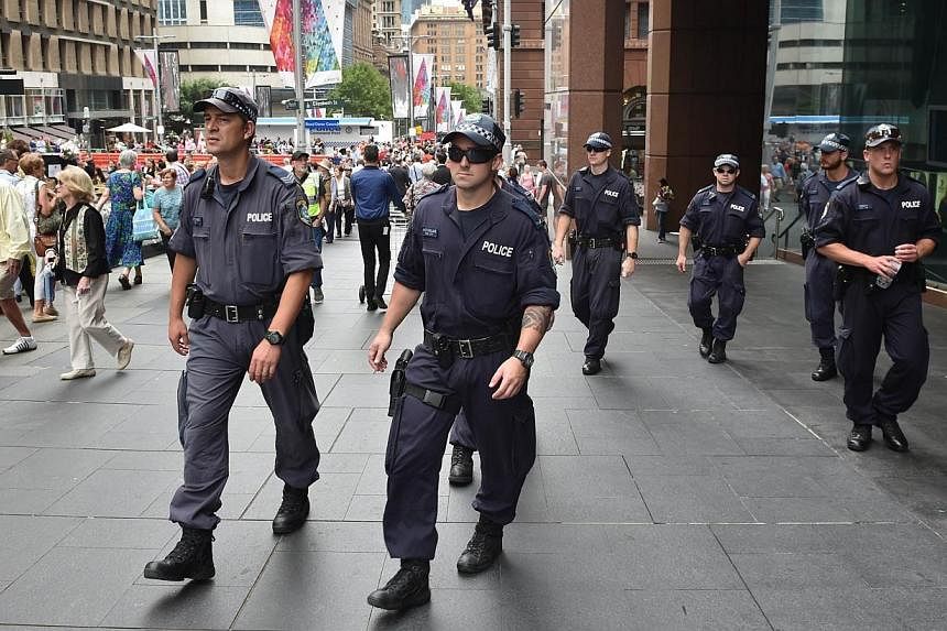 Police patrol outside the Lindt cafe, the scene of a fatal siege in the heart of Sydney's financial district, on Dec 18, 2014.&nbsp;Australian police are conducting raids across Sydney, officials said on Thursday, though the operation is not related 