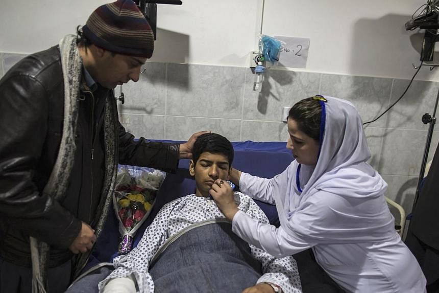Mehran Khan, 14, who survived an attack by Taliban gunmen on the Army Public School, received his medicine as he lies on a hospital bed in Peshawar on Dec 17, 2014.&nbsp;Students grieving for their classmates massacred by the Pakistani Taleban Thursd