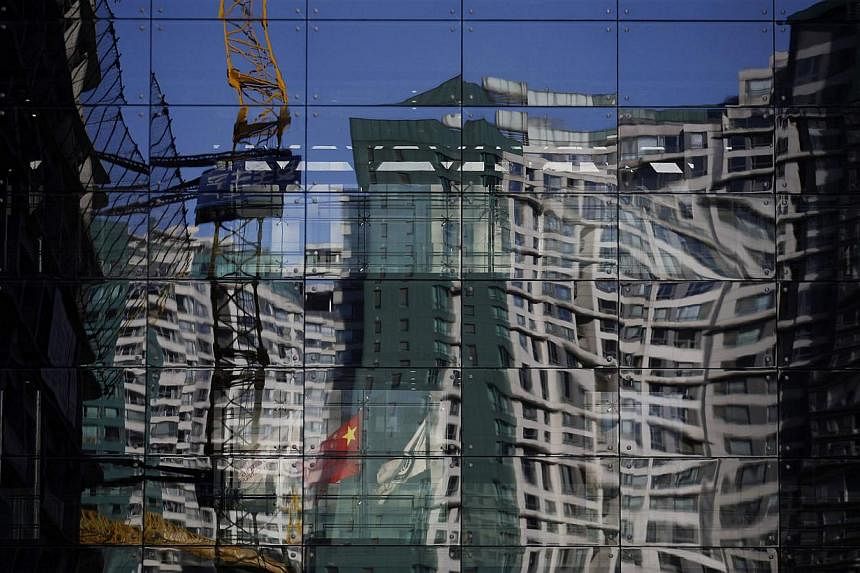 A construction site and a residential building reflected on the glass wall of a building in Beijing on Dec 15, 2014. &nbsp;China's home prices fell in November for a third consecutive month versus year-ago levels, pointing to a persistent property do