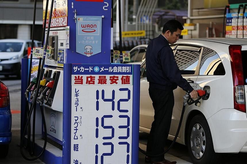 A man refuels a vehicle at a petrol station in Tokyo on Dec 17, 2014. Oil prices edged higher in Asia Thursday after data showed US stockpiles dipping, while the Federal Reserve indicated interest rates would not be hiked until the middle of next yea