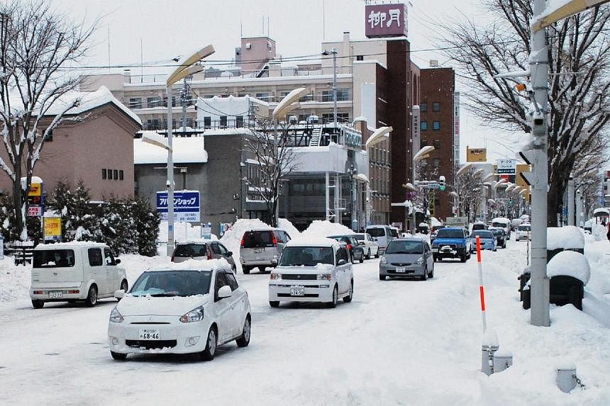 Vehicles are seen on a snow-covered street in Obihiro in Japan's northern island of Hokkaido on Dec 17, 2014. -- PHOTO: AFP