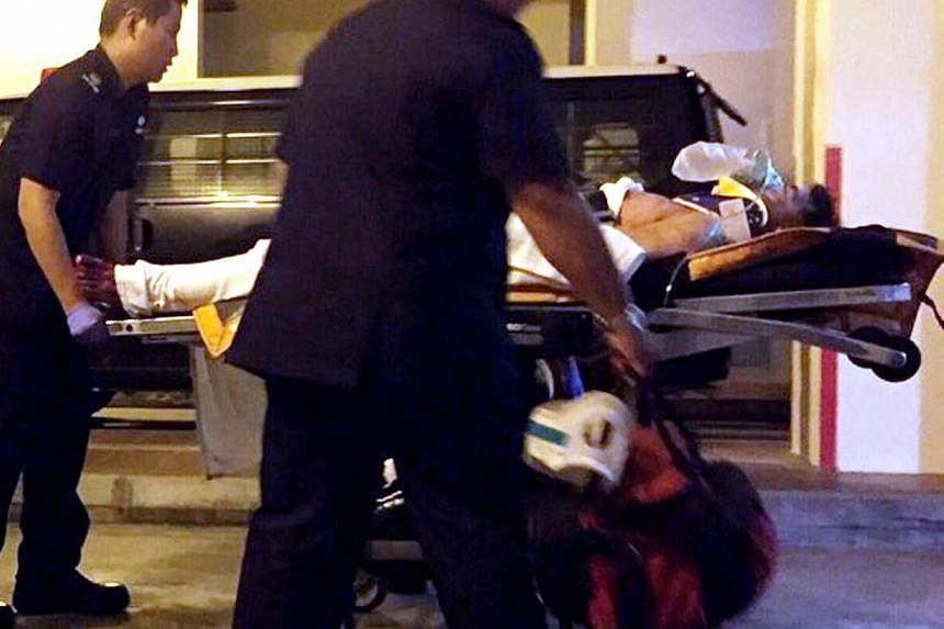 A person believed to be the suspect in the the alleged murder of a woman at a HDB block in Tampines is attended to by paramedics on Dec 17, 2014. -- PHOTO: SHIN MIN