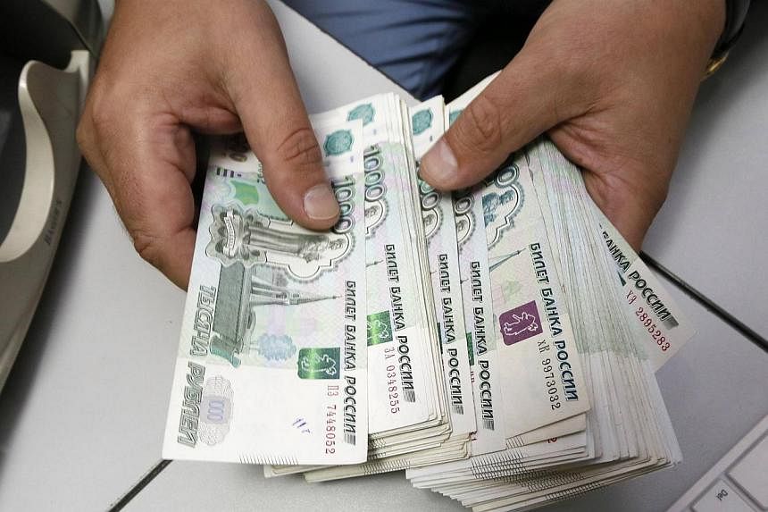 An employee counts Russian ruble banknotes at an office in Krasnoyarsk, Siberia, on Dec 17, 2014. -- PHOTO: REUTERS