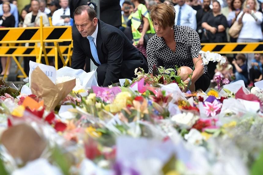 Australian Prime Minister Tony Abbott and his wife Margaret lay wreaths at a makeshift memorial near the scene of a fatal siege in the heart of Sydney's financial district on Dec 16, 2014. -- PHOTO: AFP