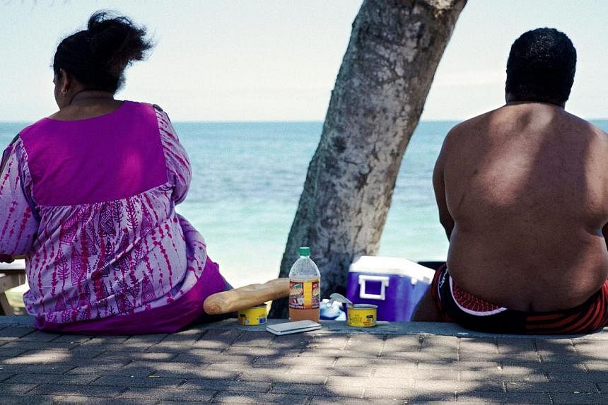 People sit along the beach looking out at sea in Noumea on Dec 1, 2014. -- PHOTO: AFP