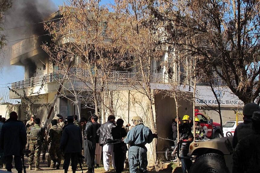 Afghan security forces keep watch as smoke rises from the site of an attack by Taleban suicide bombers at a branch of the Kabul Bank in Lashkar Gah, capital city of Helmand province on Dec 17, 2014.&nbsp;The departure of most foreign troops from Afgh