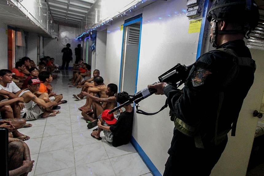 This file photo taken on Dec 16, 2014 shows National Bureau of Investigation (NBI) operatives rounding up inmates inside New Bilibid Prison in Muntinlupa, south of Manila. -- PHOTO: AFP