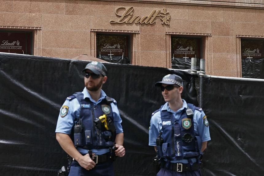 New South Wales police officers guard a post near the fenced-off site of the siege at the Lindt cafe in Martin Place, Sydney, Australia on Dec 17, 2014. -- PHOTO: REUTERS