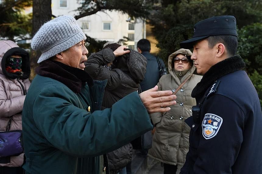 A relative of a passenger from missing Malaysia Airlines flight MH370 speaks with a policeman outside the Foreign Ministry in Beijing on Dec 19, 2014. -- PHOTO: AFP