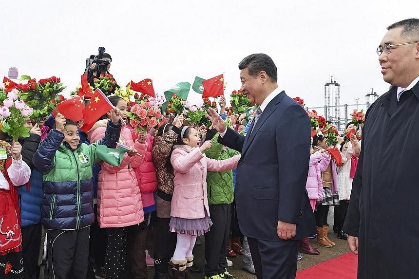 Chinese President Xi Jinping (2nd right) waves to children waving Chinese national flags and the flag of Macau, as Macau Chief Executive Fernando Chui Sai-On watches, after Xi arrived in Macau to celebrate the 15th anniversary of its handover to the 
