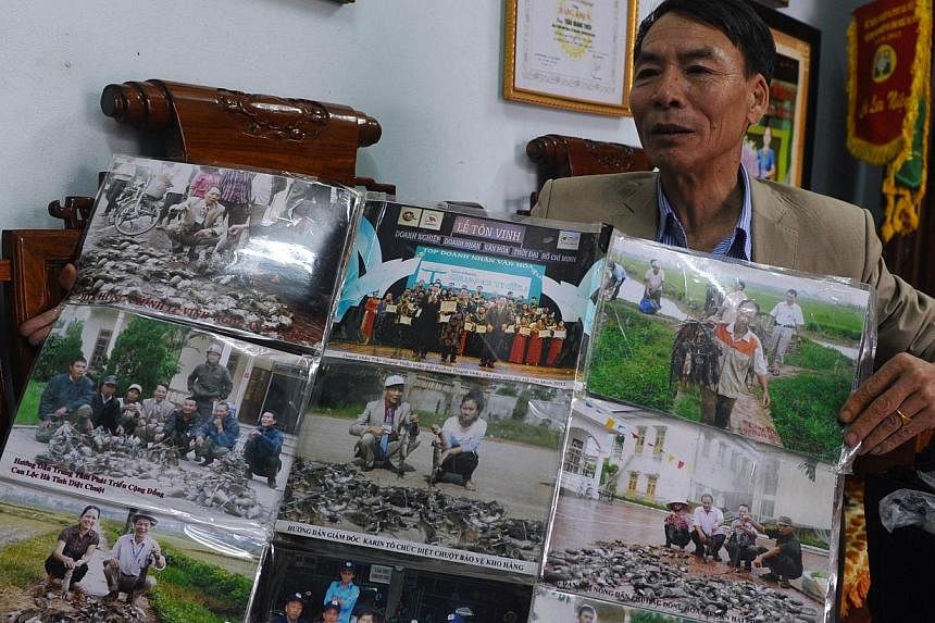 &nbsp;Mr Tran Quang Thieu shows photographs of his rat-killing records in different areas in Vietnam during an interview with AFP at his home on the outskirts of Hanoi on March 3, 2014. -- PHOTO: AFP &nbsp;P