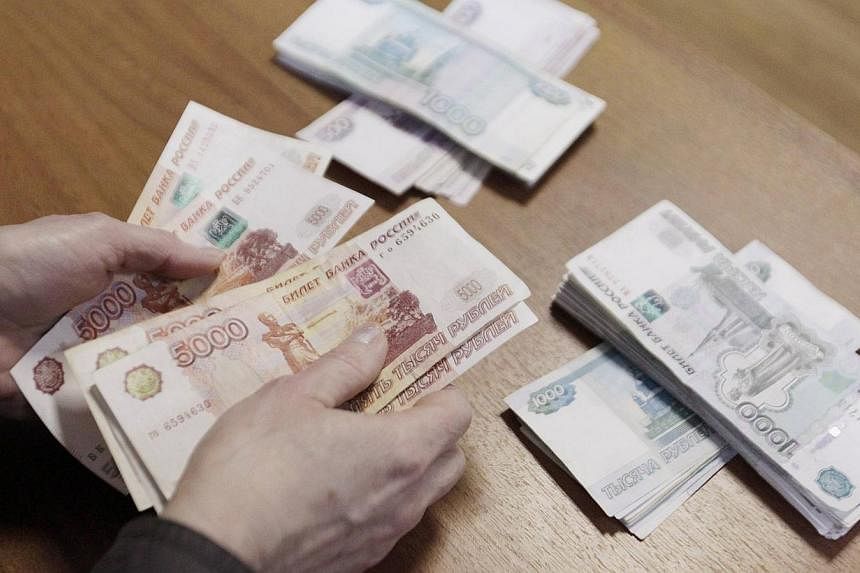 An employee of a local company, producing equipment for electrical meters, counts Russian rouble banknotes in Stavropol, southern Russia on Dec 17, 2014. -- PHOTO: REUTERS