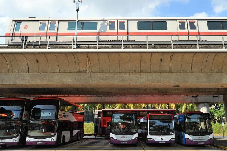 SBS buses parked under the SMRT track while an SMRT train passes by the Yio Chu Kang bus interchange on July 21, 2014.&nbsp;Both public transport operators SMRT and SBS Transit have submitted their applications for fare adjustments to the Public Tran