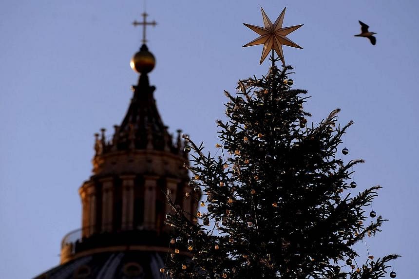 A silhouette of the Christmas pine tree set in front of St Peter's basilica is on Dec 19, 2014, before a lighting-up ceremony. -- PHOTO: AFP