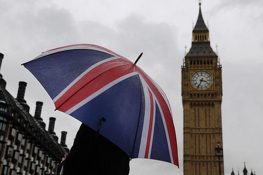 A person holds a Union flag umbrella in front of the Big Ben clock tower and Houses of Parliament in London, Britain, on Oct 4, 2014. A Singaporean who sees himself as a woman has failed in his bid to remain in the country on human rights grounds. --