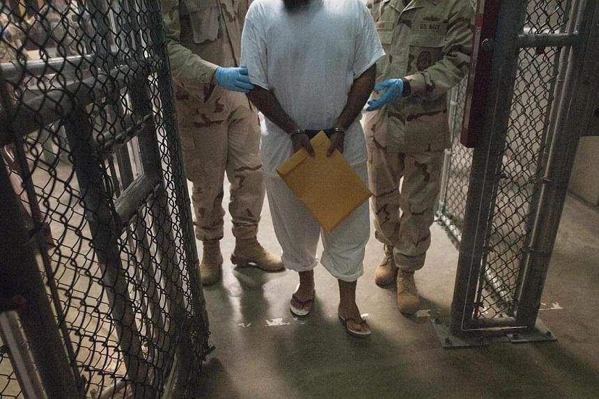 A file photo&nbsp;shows US military guards as they move a detainee at Guantanamo Bay, Cuba.&nbsp;Four detainees held at the Guantanamo Bay US military prison have been repatriated to Afghanistan, the Pentagon said Saturday. -- PHOTO: AFP