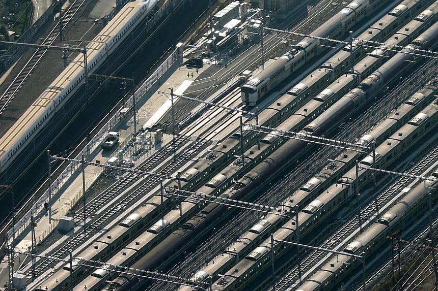 A Central Japan Railway Co. Shinkansen bullet train, left, travels near East Japan Railway Co. trains in this aerial photograph taken in Tokyo, Japan, on Monday, Dec. 2, 2013. Thailand is talking to Japan with a view to building three rail routes in 