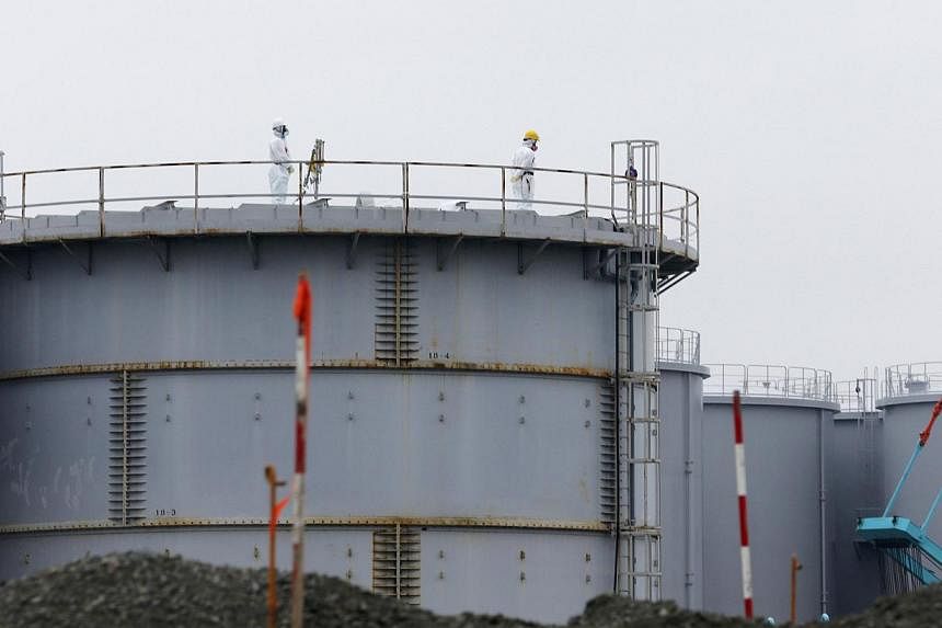 Workers wearing radiation protective gear stand on a water tank storing radiation contaminated water at TEPCO's tsunami-crippled Fukushima Daiichi nuclear power plant in Fukushima prefecture on Nov 12, 2014. A 5.9 magnitude earthquake hit Japan’s H