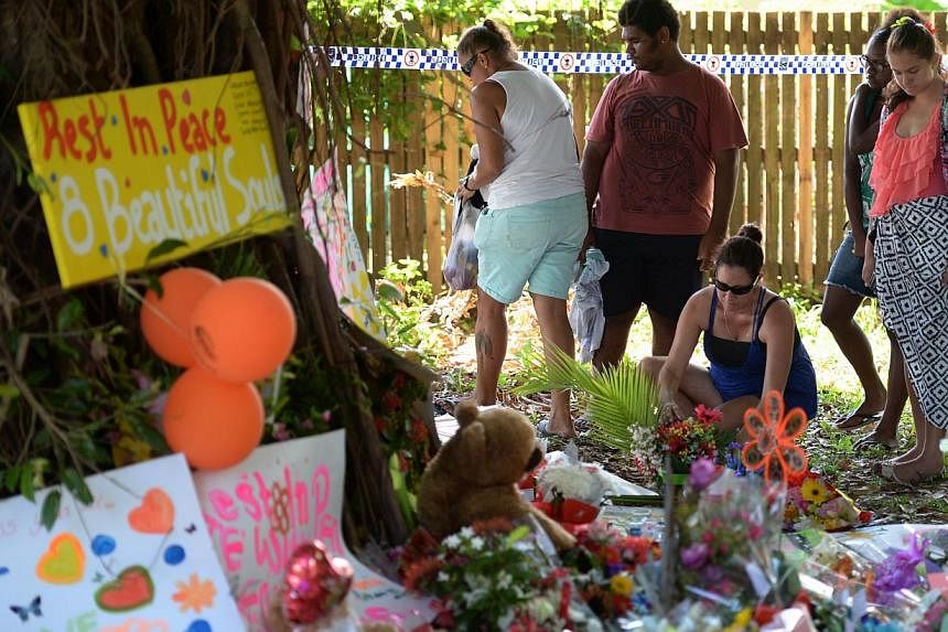 Mourners at the scene where eight children ranging from babies to teenagers were found dead in a house in the northern Australian city of Cairns. A 37-year-old woman, the mother of all but one of the eight children, has been charged with eight counts