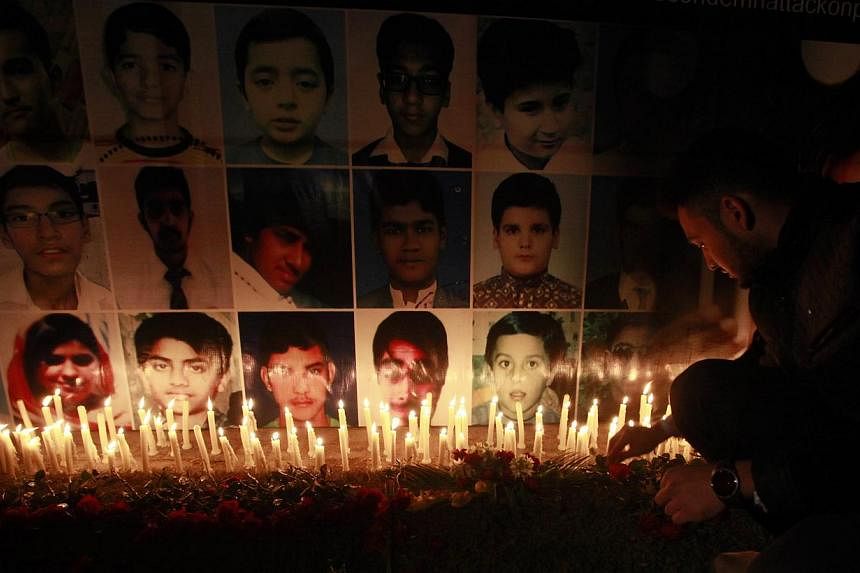 A man places a rose after lighting candles in front of portraits of the victims of the Taleban attack on the Army Public School in Peshawar, during a candlelight vigil in Lahore on Dec 19, 2014.&nbsp;Al-Qaeda's regional branch on Sunday, Dec 21, said