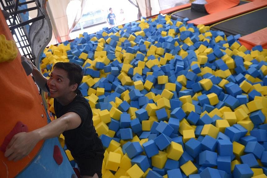 Reporter Benson Ang jumping onto the 11m-long airbag, which is accessible via five lanes and climbing (above) the 3.5m-high rock wall at Zoom Park Singapore, from which climbers can fall safely into the foam pit below.&nbsp;--&nbsp;ST PHOTO: MARK CHE