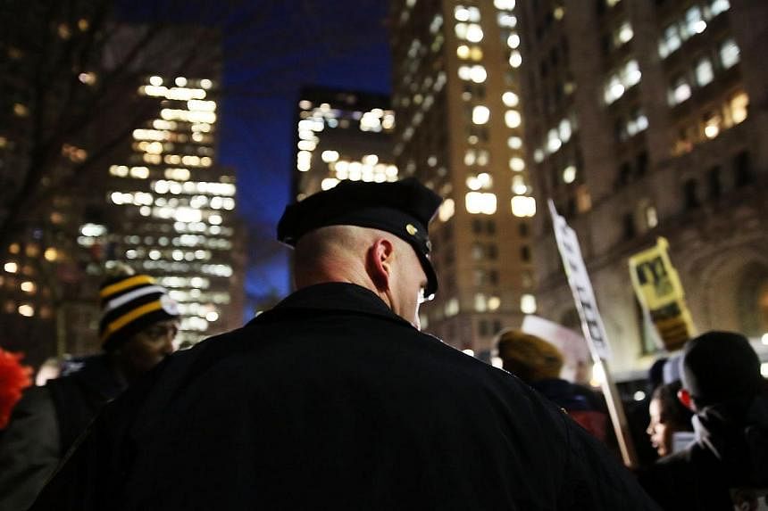 A police officer stands guard as people demonstrate outside City Hall against police violence at a rally that was supposed to be in support of the New York Police Department on Dec 19, 2014 in New York City.&nbsp;Two New York police officers were sho