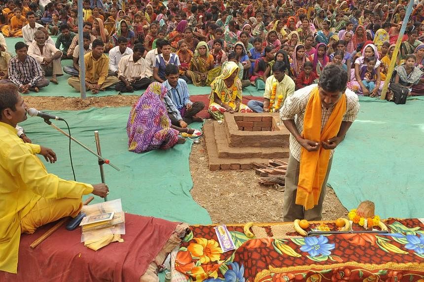 An Indian tribesperson (R, foreground) participates in a conversion ritual of some 200 Christians into Hinduism, at Aranai Village in Valsad district of Gujarat state, some 350 kms from Ahmedabad, on December 20, 2014. Hardline Hindu groups came unde