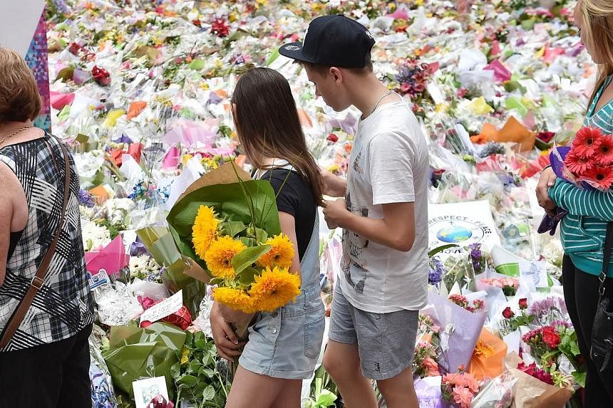 Visitors carry flowers to lay at a makeshift memorial near the scene of the fatal siege in the heart of Sydney's financial district, on Dec 18, 2014. Amirah Droudis, the partner of a self-styled Sheikh who last week stormed the cafe at gunpoint, has 