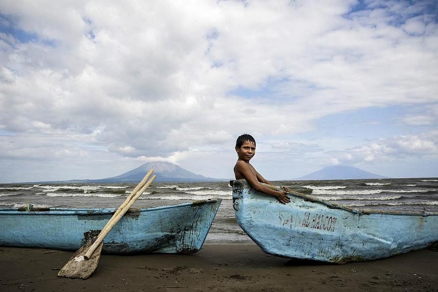 A boy is seen sitting in a boat along the shore of Cocibolca lake in Rivas, Nicaragua on Dec 11, 2014.&nbsp;The construction of Nicaragua's controversial US$50-billion (S$62.52 billion) canal linking the Pacific Ocean and the Caribbean begins Monday,