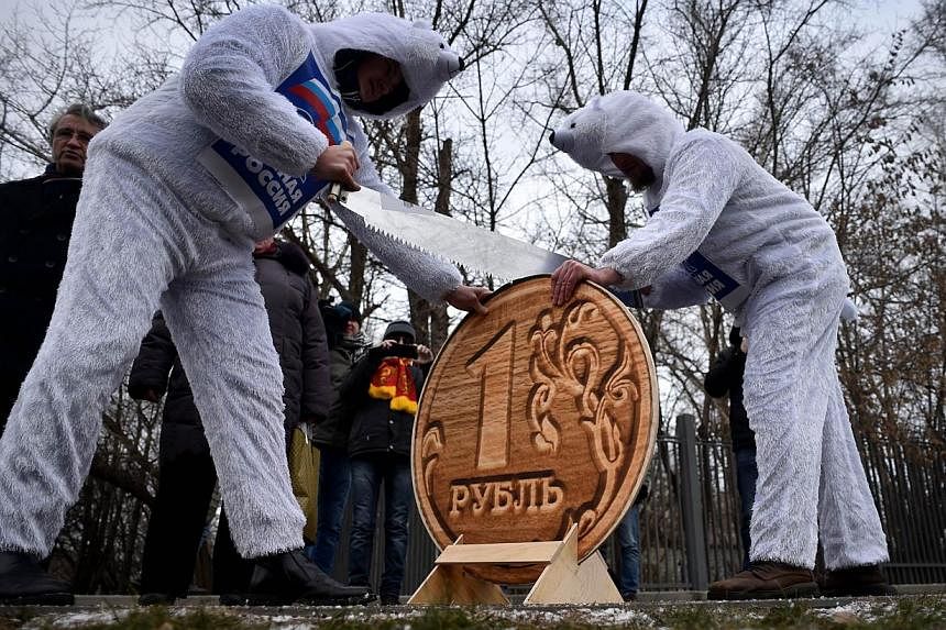Russia's Communist Party supporters dressed as white bears, symbol of pro-President party United Russia, saw a model of a one Russian ruble coin during a rally against ruble fall in exchange in front of the headquarters of the government in central M