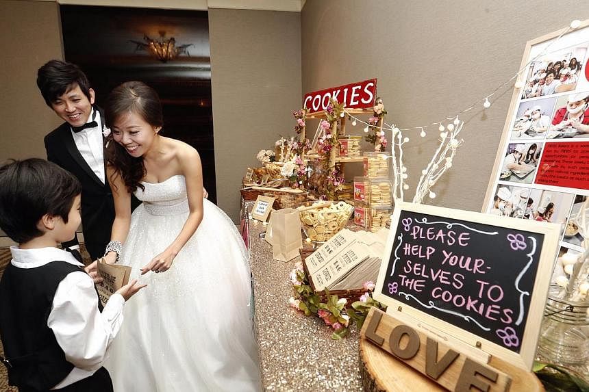 Ms Sue-Ann Phay, in her early 30s, and Mr Boaz Chan, 30, giving out cookies at their wedding reception last Saturday. The counter had a write-up and photos explaining that the cookies were baked by clients from the Movement for the Intellectually Dis