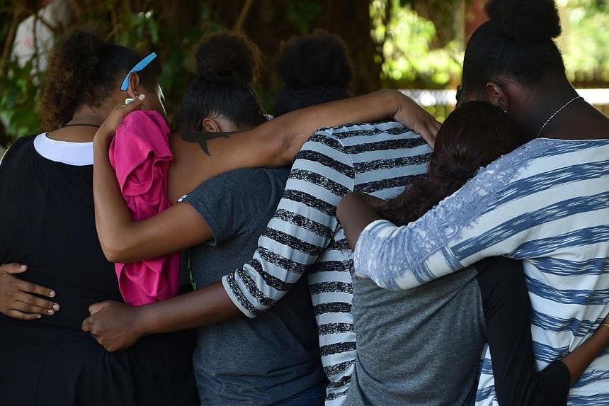 This photo taken on Dec 20, 2014 shows people hugging at the scene where eight children ranging from babies to teenagers were found dead in a house in the northern Australian city of Cairns. -- PHOTO: AFP&nbsp;