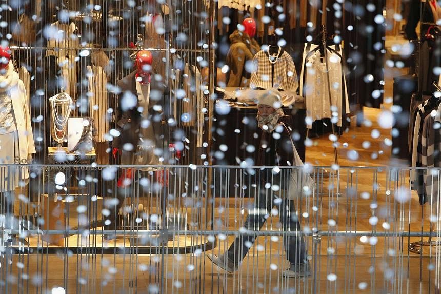 A woman walks past a shop window at a department store in Tokyo on Dec 19, 2014. -- PHOTO: REUTERS