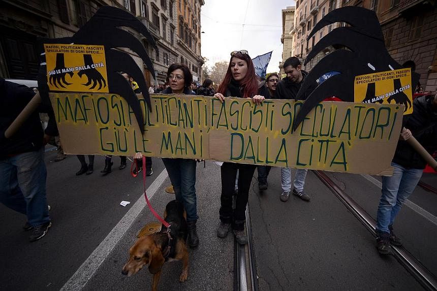 Demonstrators hold a banner, reading "Mafiosi, politicians, fascists, speculators hands off the city", during a rally on Dec 13, 2014 following the recent Rome anti-mafia sweep in downtown Rome. -- PHOTO: AFP