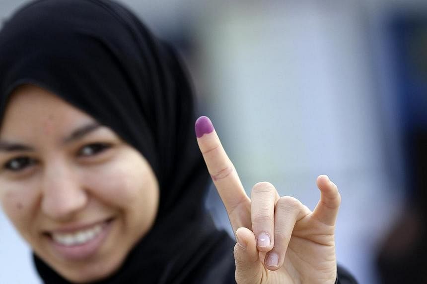 A woman shows her ink-stained finger after casting her vote at a polling station in Tunis on Sunday. Tunisians began voting on Sunday in a presidential run-off election that completes the country's last steps to full democracy nearly fours years afte