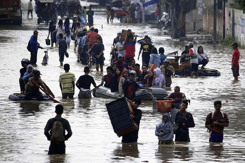 People walk through a flooded street after heavy rain hit an industrial estate area in Bandung regency, on Dec 22, 2014. -- PHOTO: REUTERS