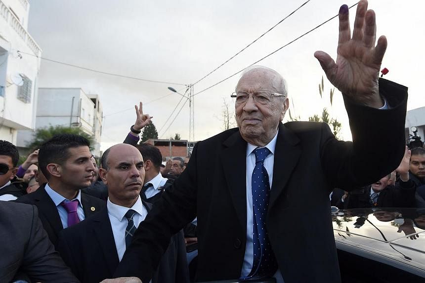 Tunisian presidential candidate for the anti-Islamist Nidaa Tounes party, Beji Caid Essebsi waves to supporters after placing his vote on Dec 21, 2014 in Tunis. -- PHOTO: AFP