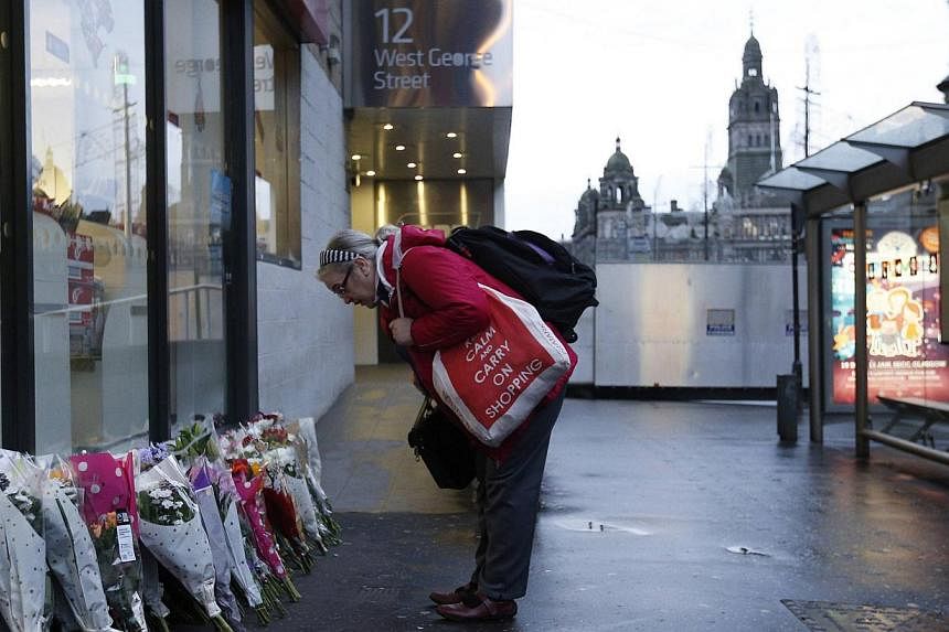 A woman looks at flowers close to the scene where a refuse truck crashed into pedestrians in George Square, Glasgow, Scotland on Dec 23, 2014. -- PHOTO: REUTERS