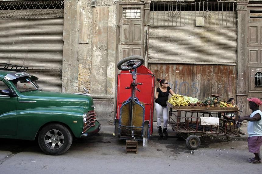 People stand next to a cart with fruit on a street in downtown Havana Dec 17, 2014.&nbsp;US businesses are lining up to take advantage of the enormous investment potential of Cuba, all but untouched for more than half-a-century by American capitalism