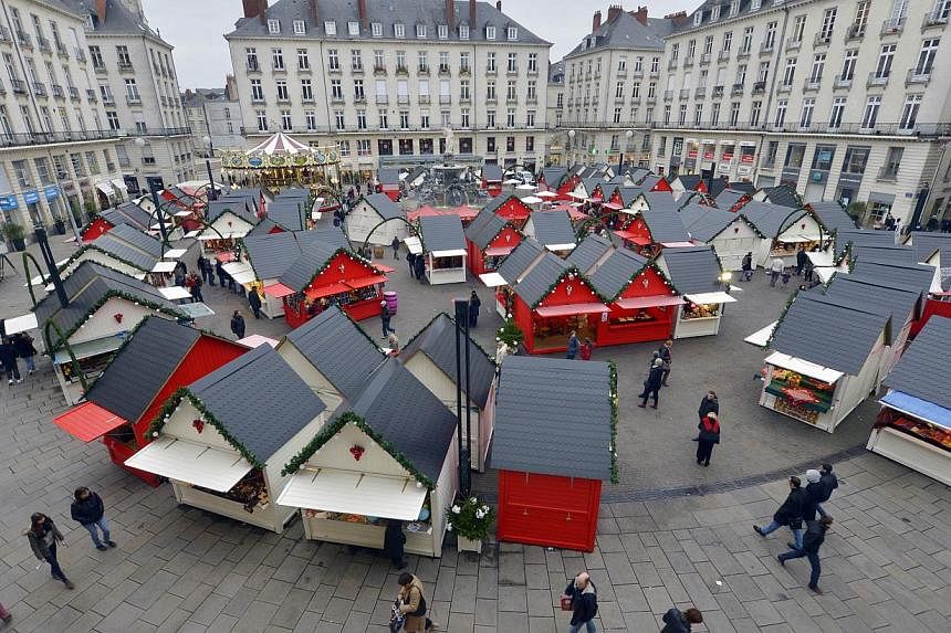 People visit the Christmas market in the western French city of Nantes on Dec 23, 2014, a day after a man rammed into shoppers with his car. -- PHOTO: AFP